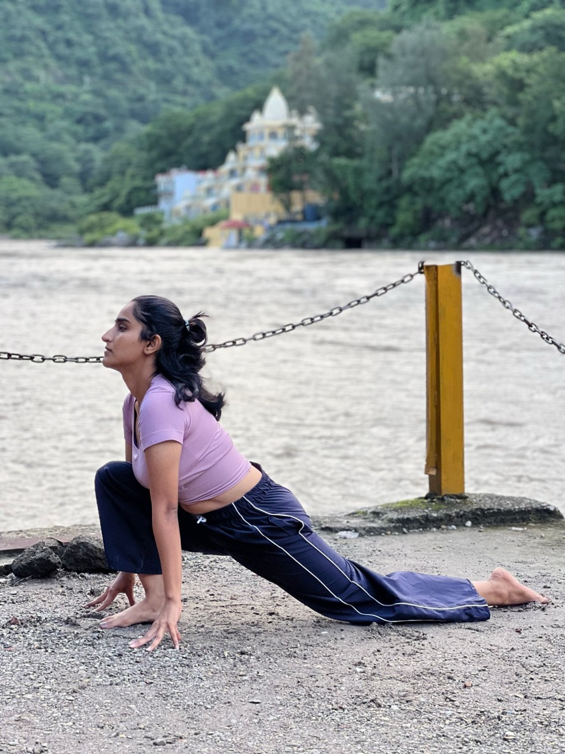 Vandana Bhaskar in a low lunge by the Ganga in Rishikesh